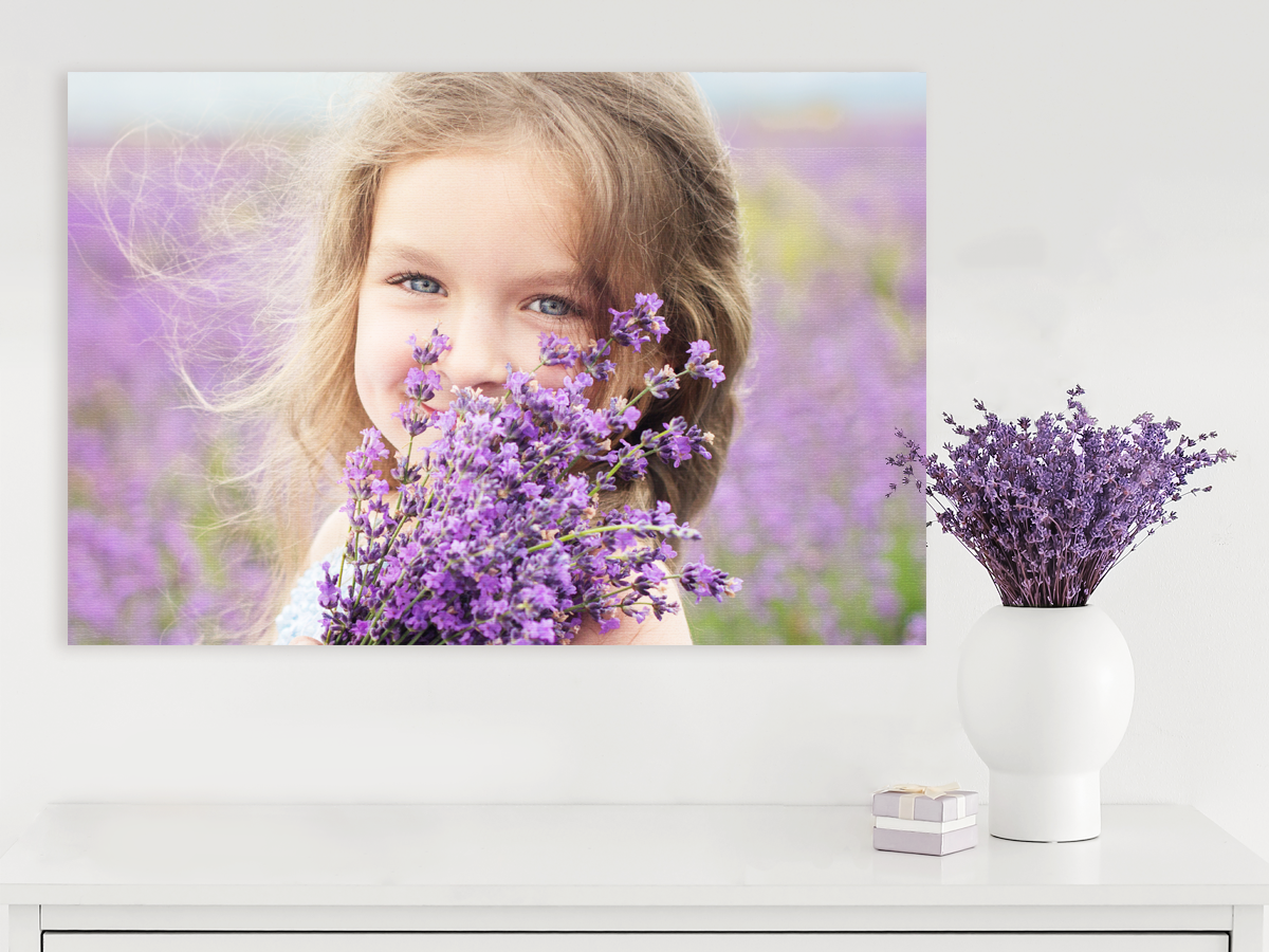 Canvas Gallery Wrap of a young girl holding flowers hanging above a table.